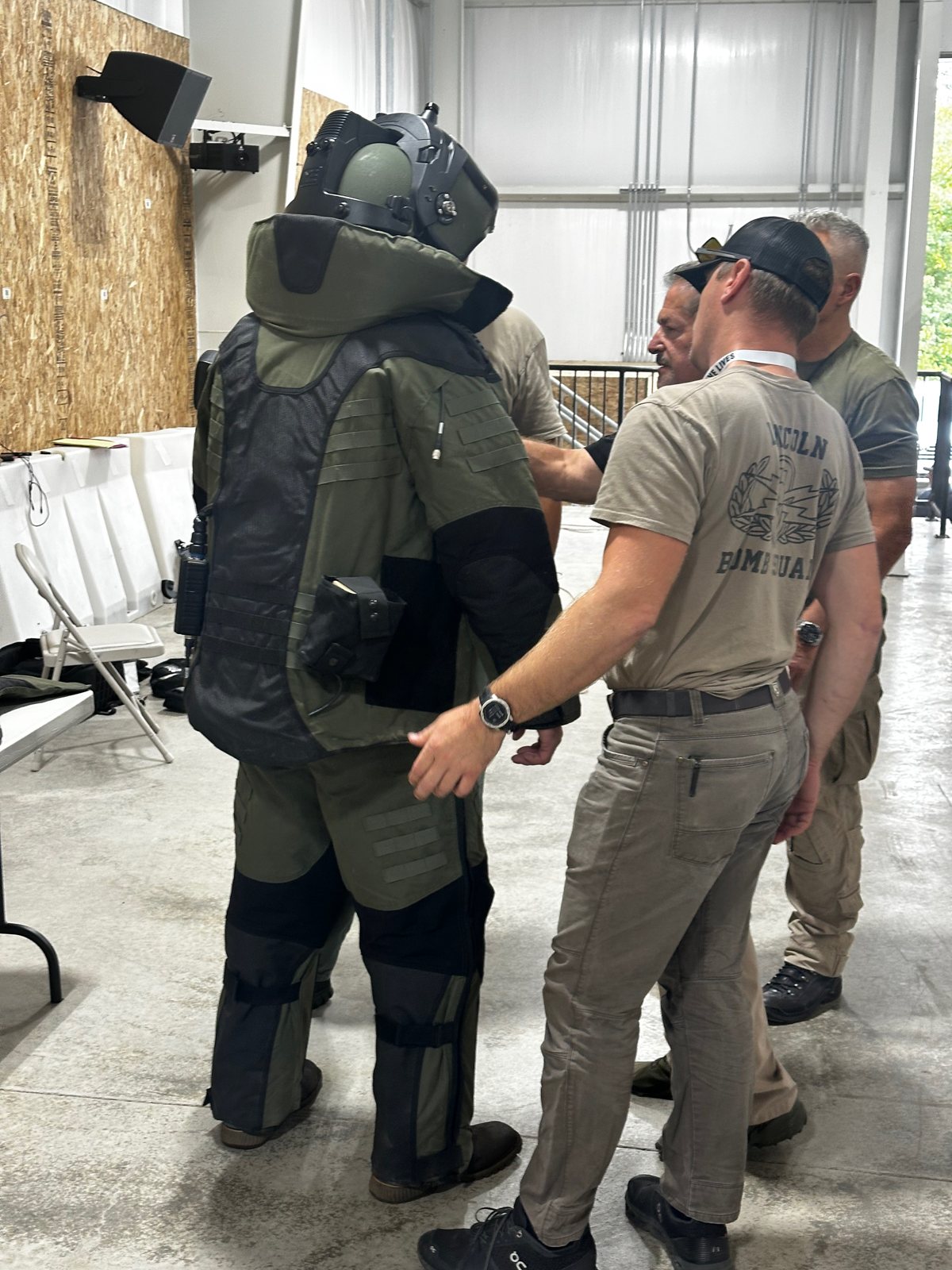 Bomb technician being dressed out in a bomb suit before a training lane